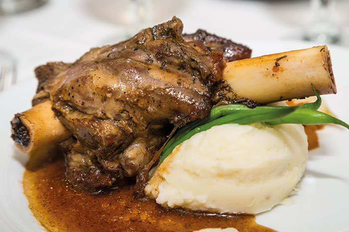 A lamb shank on mash with vegetables and gravy