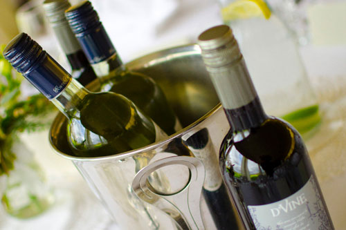Two bottles of wine in an ice bucket and a bottle of red wine on the table